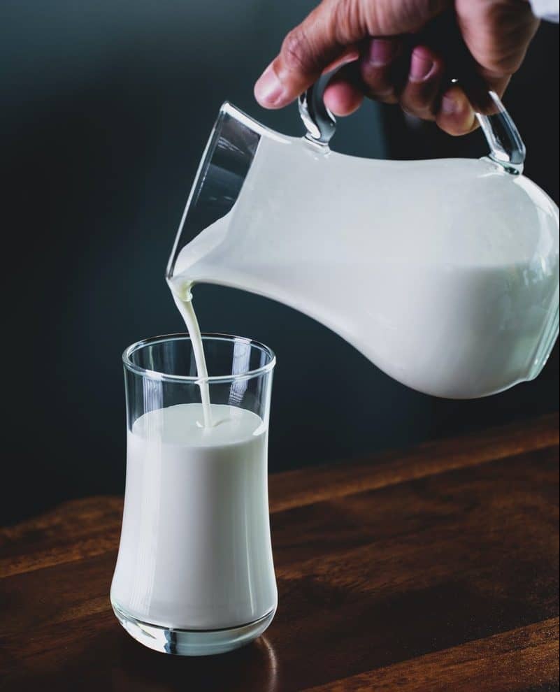 person pours milk into glass